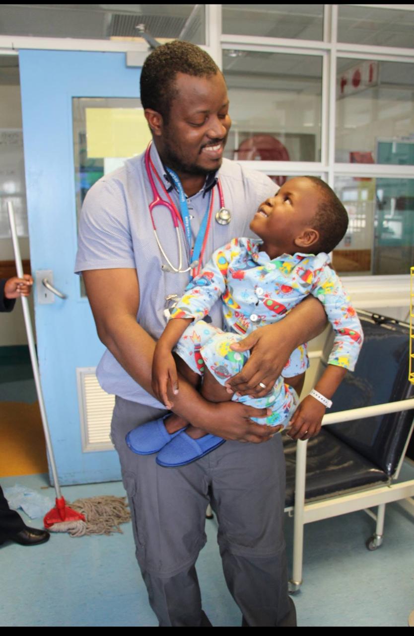 Dr A A Jalloh supporting a young child in a hospital setting